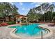 A stunning community pool features a covered gazebo, lush landscaping, and plenty of lounge chairs at 2171 Portofino Pl # 27-2725, Palm Harbor, FL 34683