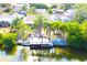 Waterfront home featuring a private dock, boat and lush landscaping along the water's edge at 2211 Harrison Dr, Holiday, FL 34691