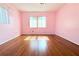 Bright pink bedroom with gleaming hardwood floors and natural light at 2211 Harrison Dr, Holiday, FL 34691