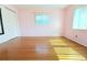 Clean pink bedroom featuring hardwood floors, a closet, and natural light at 2211 Harrison Dr, Holiday, FL 34691