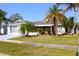 Inviting home featuring mature trees, well-maintained landscaping, and a screened-in front porch at 2211 Harrison Dr, Holiday, FL 34691