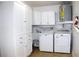 Laundry room with front-loading washer/dryer, utility sink, and ample cabinet space at 2211 Harrison Dr, Holiday, FL 34691