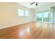 Open living room with hardwood floors, fan and sliding glass door to sunroom at 2211 Harrison Dr, Holiday, FL 34691