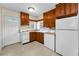 Galley kitchen with wood cabinets, white appliances, and a window above the sink at 224 Georgia Ave, Crystal Beach, FL 34681