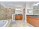 Bright bathroom boasts dual sink vanity, soaking tub, and step-in shower with designer tile accent at 2566 Lake Manor Dr, Land O Lakes, FL 34639