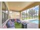 Cozy covered patio offers comfortable seating area, ceiling fan, and sliding sunshade with a view of the pool at 2566 Lake Manor Dr, Land O Lakes, FL 34639