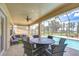 Covered patio featuring tile flooring, ceiling fan, dining area, and view of pool and landscaped backyard at 2566 Lake Manor Dr, Land O Lakes, FL 34639