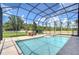 Sparkling screened-in pool with spa and lake views, surrounded by lush greenery and outdoor seating at 2566 Lake Manor Dr, Land O Lakes, FL 34639