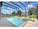 Sparkling screened-in pool with spa and lake views, surrounded by lush greenery and outdoor seating at 2566 Lake Manor Dr, Land O Lakes, FL 34639