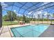 Gorgeous screened-in pool with adjacent spa and beautiful lawn with palm trees and lake view at 2566 Lake Manor Dr, Land O Lakes, FL 34639