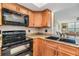 A kitchen with wooden cabinets, granite countertops, and black appliances at 2621 Cove Cay Dr # 302, Clearwater, FL 33760