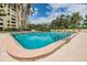 Enjoy a refreshing swim in the outdoor pool featuring palm trees and lounge chairs, perfect for relaxation at 2621 Cove Cay Dr # 302, Clearwater, FL 33760