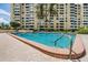 Community pool with lounge chairs and palm trees against the backdrop of the condo building at 2621 Cove Cay Dr # 302, Clearwater, FL 33760