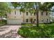 Two-story home with tan stucco, red tile roof, arched entry and brick driveway with mature landscaping at 2900 W Estrella St, Tampa, FL 33629