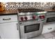 Close-up of a Wolf stainless steel oven, cooktop, and oven with white cabinets and black countertops at 2900 W Estrella St, Tampa, FL 33629