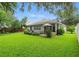 Expansive backyard featuring lush green grass, mature trees, a covered patio, and a well-maintained garden area at 3101 Beaver Pond Trl, Valrico, FL 33596