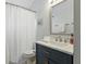 Modern bathroom with a navy blue vanity, a marble countertop, and a shower with a white curtain at 3101 Beaver Pond Trl, Valrico, FL 33596