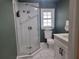 Modern bathroom with tiled shower, hexagon tile floor, and a dark green accent wall at 318 W Crest Ave, Tampa, FL 33603