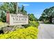 An inviting sign for Woodside Village Condominiums, a no-pet community with lush landscaping at 4215 E Bay Dr # 1801E, Clearwater, FL 33764