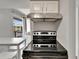A modern kitchen with stainless steel range hood, black glass top range, and white cabinets at 4215 E Bay Dr # 1801E, Clearwater, FL 33764