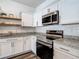 Bright kitchen features stainless appliances, granite countertops, white cabinets and floating shelves at 4338 Banjo Lake Rd, Land O Lakes, FL 34639