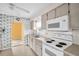 Kitchen features vintage cabinets, white appliances and patterned wallpaper at 5720 13Th N Ave # 207B, St Petersburg, FL 33710