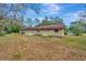 Backyard view of home with stucco walls, brown roof, a window, and a sliding glass door at 5749 Southernview Dr, Zephyrhills, FL 33541