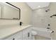 A bathroom with white marbled walls, white cabinets, black hardware, and a white tub at 5749 Southernview Dr, Zephyrhills, FL 33541