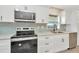 Kitchen with stainless steel oven, microwave, white cabinets, and attractive blue tile backsplash at 5749 Southernview Dr, Zephyrhills, FL 33541