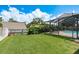 Spacious backyard featuring a screened pool enclosure, lush green grass, and a privacy fence at 630 Kirkland Cir, Dunedin, FL 34698