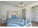 Cozy bedroom with a ceiling fan, closet with shelving, and a bed with blue and white patterned bedding at 630 Kirkland Cir, Dunedin, FL 34698