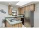 Bright kitchen with stainless steel refrigerator, cooktop, and light wood cabinetry with view to the outdoors at 630 Kirkland Cir, Dunedin, FL 34698