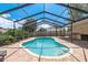 Large screened-in pool with brick paver patio, lush landscaping, and beautiful blue skies at 630 Kirkland Cir, Dunedin, FL 34698