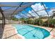 In-ground screened-in swimming pool with brick paver patio and lounge chairs in a tropical backyard setting at 630 Kirkland Cir, Dunedin, FL 34698