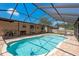 Screened-in pool with brick paver patio, outdoor kitchen, and lounge chairs in a tropical backyard setting at 630 Kirkland Cir, Dunedin, FL 34698