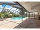 Screened-in swimming pool with outdoor lounge chairs, a brick paver patio, and lush landscaping at 630 Kirkland Cir, Dunedin, FL 34698