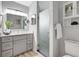 Modern bathroom featuring gray vanity with double mirrors and a framed, frosted glass shower at 6603 S Juanita St, Tampa, FL 33616