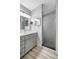 Modern bathroom featuring gray vanity with double mirrors and a framed, frosted glass shower at 6603 S Juanita St, Tampa, FL 33616