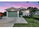 Charming single-story home with a well-manicured lawn, and a one car garage under a vibrant dusk sky at 6603 S Juanita St, Tampa, FL 33616