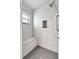 Newly tiled shower featuring a window, a built-in seat, and a handheld shower head at 6603 S Juanita St, Tampa, FL 33616