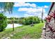 Backyard with well-maintained lawn, beautiful landscaping, and view of a picturesque pond at 7305 Jasmine Blvd, Port Richey, FL 34668