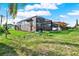 The backyard features lush green grass surrounding the screened-in lanai, adjacent to the main storage building at 7305 Jasmine Blvd, Port Richey, FL 34668