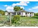 Charming home exterior featuring well-maintained landscaping, flowering bushes, and an American flag at 7305 Jasmine Blvd, Port Richey, FL 34668