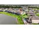 Aerial view showcasing a home with a screened pool enclosure near a pond in a residential neighborhood at 7570 Sweeter Tide Trl, Wesley Chapel, FL 33545