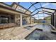 Spacious screened-in pool with covered patio area, outdoor seating, and backyard lake views at 7570 Sweeter Tide Trl, Wesley Chapel, FL 33545