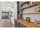 Elegant home bar area with wood countertop, gray cabinets, shelving, and wine storage in a stylish, modern design at 7570 Sweeter Tide Trl, Wesley Chapel, FL 33545