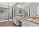 Elegant primary bathroom with dual granite vanities, large mirrors, and a glass-enclosed shower, exuding luxury at 7570 Sweeter Tide Trl, Wesley Chapel, FL 33545