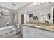 Bathroom featuring single vanity, granite countertops, modern fixtures, shower-tub, and built-in storage at 7570 Sweeter Tide Trl, Wesley Chapel, FL 33545
