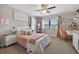 Cozy bedroom featuring plush bedding, a large window, and a modern ceiling fan at 7570 Sweeter Tide Trl, Wesley Chapel, FL 33545