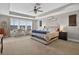 Primary bedroom featuring tray ceiling, neutral carpet, large windows and a desk area at 7570 Sweeter Tide Trl, Wesley Chapel, FL 33545